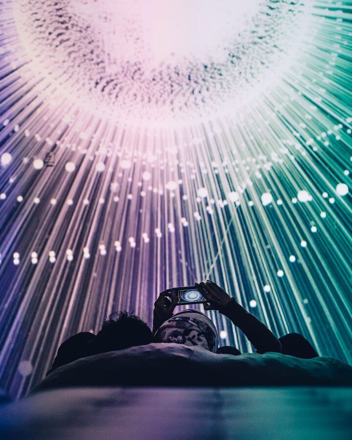 Person capturing a colorful interactive light display at a digital art exhibition