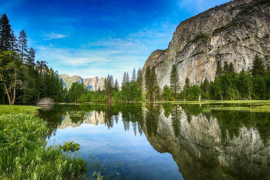 Mirror Lake in Yosemite reflecting surrounding mountains and trees on a calm day